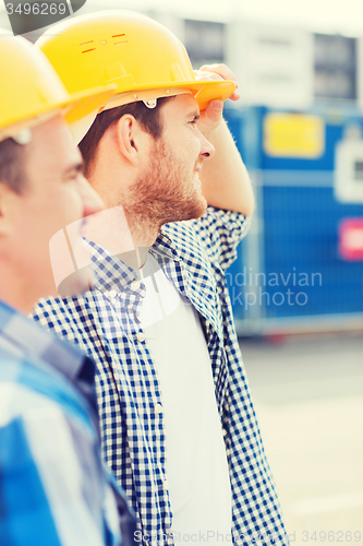 Image of group of smiling builders in hardhats outdoors