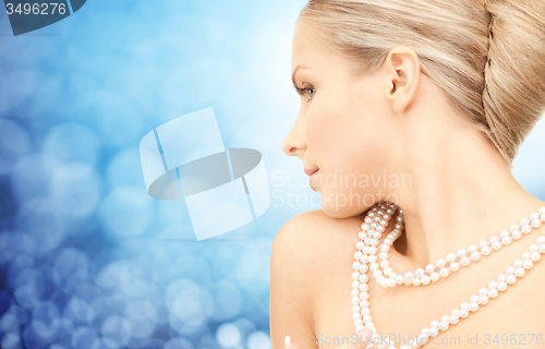 Image of beautiful woman with sea pearl necklace over blue