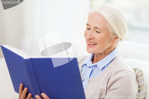 Image of happy smiling senior woman reading book at home