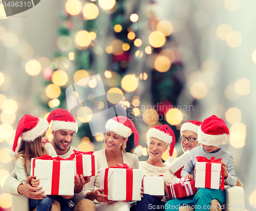 Image of happy family in santa helper hats with gift boxes