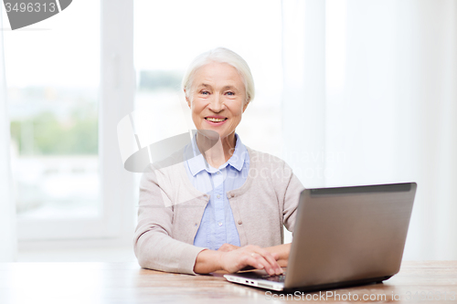 Image of happy senior woman with laptop at home