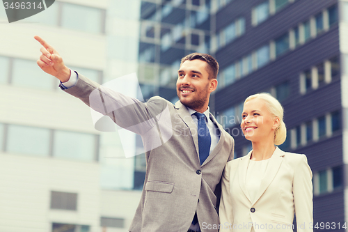 Image of smiling businessmen standing over office building