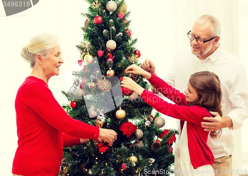 Image of smiling family decorating christmas tree at home