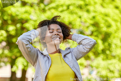 Image of happy african american young woman in summer park