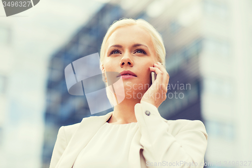 Image of serious businesswoman with smartphone outdoors