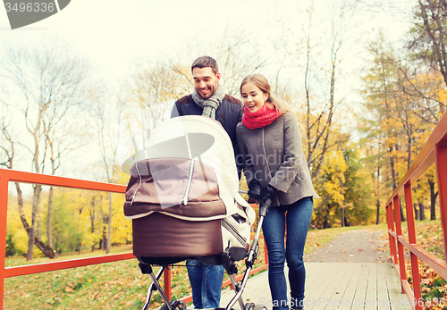 Image of smiling couple with baby pram in autumn park