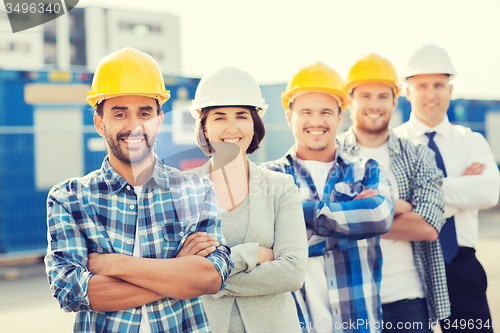 Image of group of smiling builders in hardhats outdoors