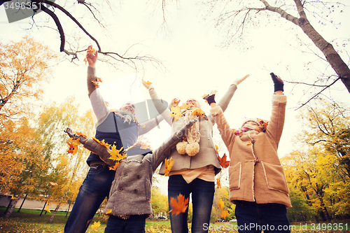 Image of happy family playing with autumn leaves in park