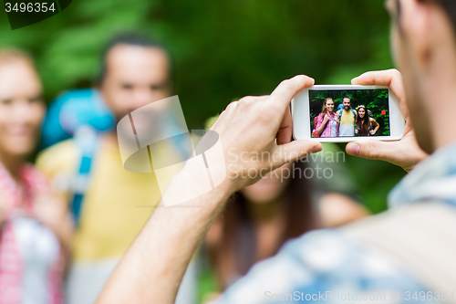 Image of man photographing friends by smartphone