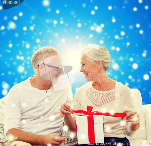 Image of happy senior couple with gift box at home