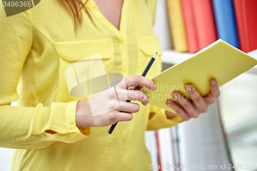 Image of close up of female hands with notebook and pencil