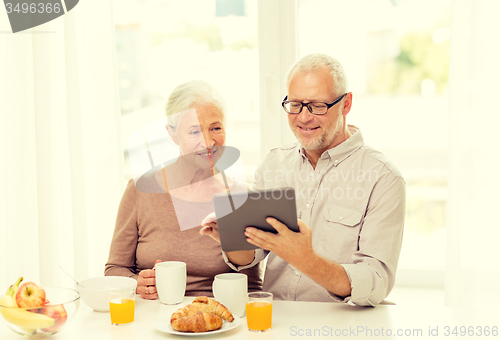 Image of happy senior couple with tablet pc at home