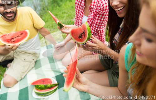 Image of happy friends eating watermelon at camping