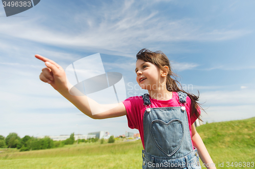 Image of happy little girl pointing finger on summer field