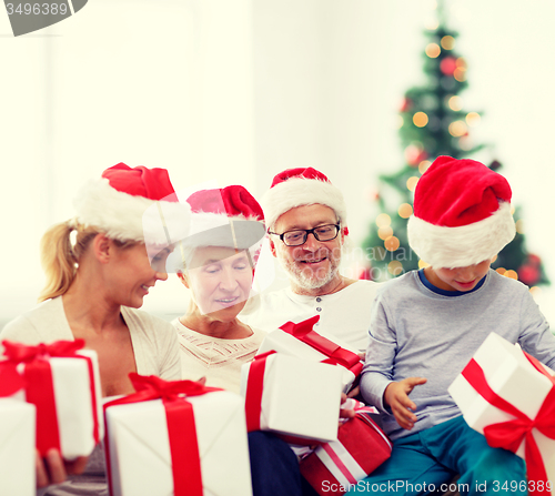 Image of happy family in santa helper hats with gift boxes