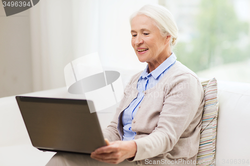 Image of happy senior woman with laptop at home