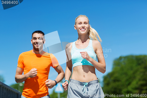 Image of smiling couple running outdoors