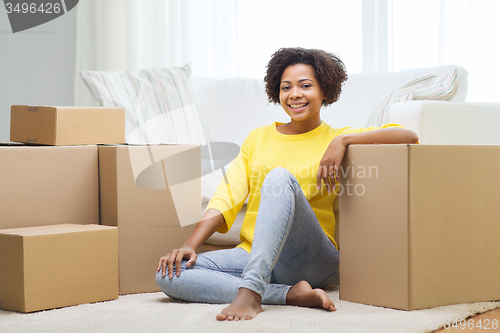 Image of happy african woman with cardboard boxes at home