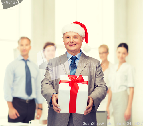 Image of smiling man in suit and santa helper hat with gift