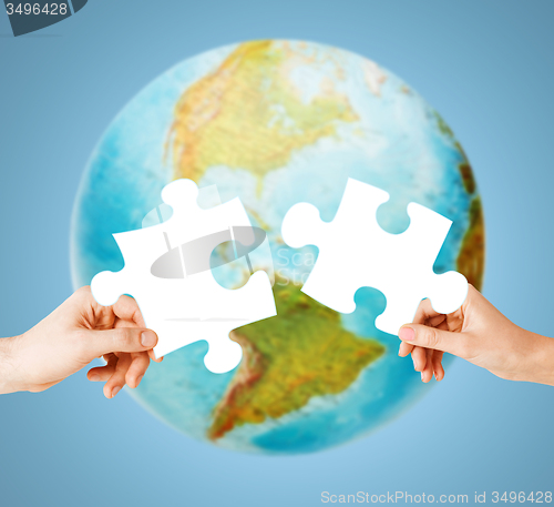 Image of hands with white blank puzzle over earth globe