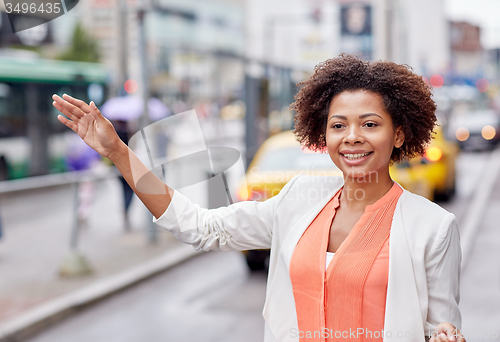 Image of happy african woman catching taxi