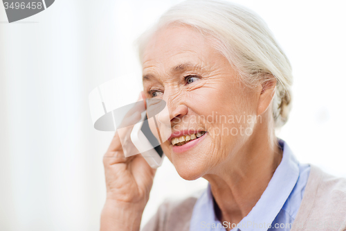 Image of senior woman with smartphone calling at home