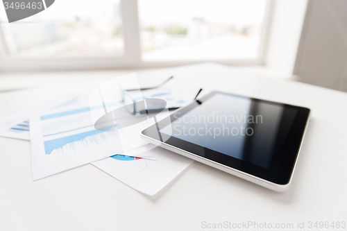 Image of close up of tablet pc, glasses and files in office