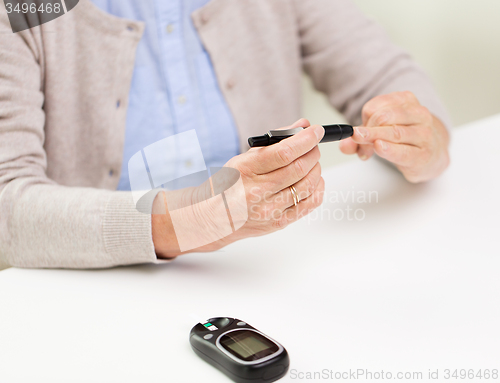 Image of senior woman with glucometer checking blood sugar