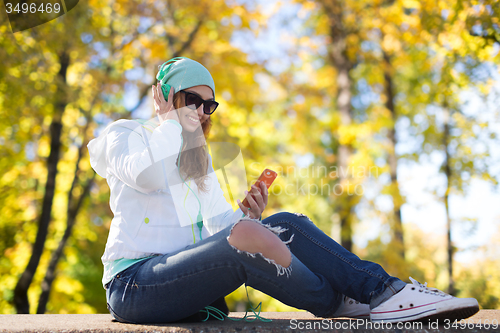 Image of happy young woman with smartphone and headphones