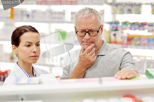 Image of pharmacist showing drug to senior man at pharmacy