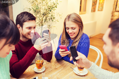 Image of group of friends with smartphones meeting at cafe