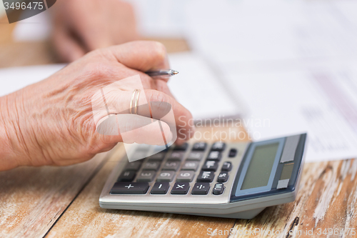 Image of close up of senior woman counting with calculator