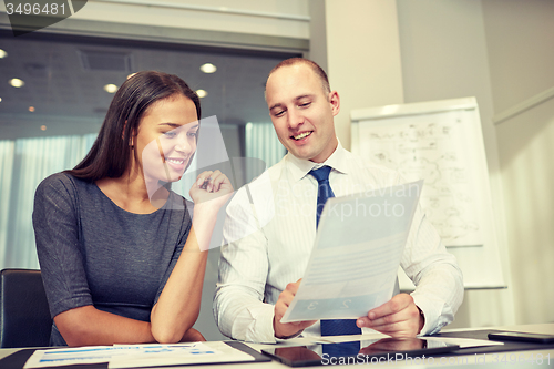 Image of smiling businesspeople with papers in office