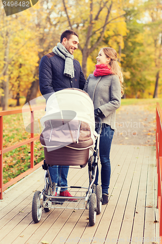 Image of smiling couple with baby pram in autumn park