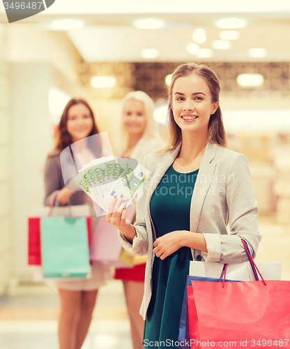 Image of young women with shopping bags and money in mall