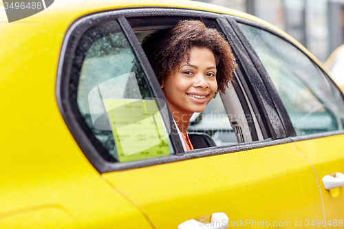 Image of happy african american woman driving in taxi