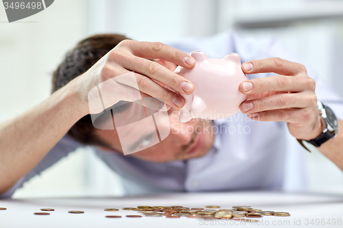 Image of businessman with piggy bank and coins at office