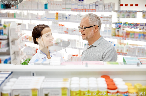 Image of happy pharmacist talking to senior man at pharmacy