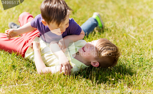 Image of happy little boys fighting for fun on grass