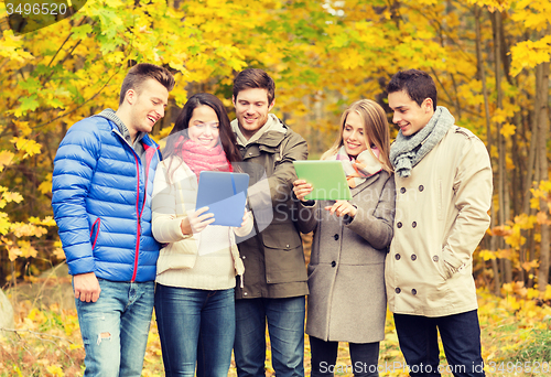 Image of group of smiling friends with tablets in park