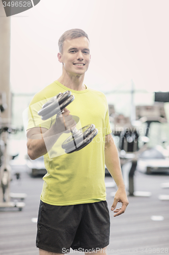 Image of smiling man with dumbbell in gym