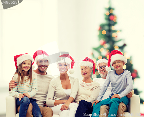 Image of happy family in santa helper hats sitting on couch