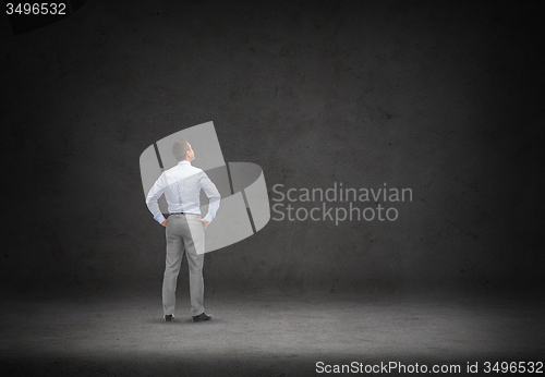 Image of businessman looking at concrete wall background