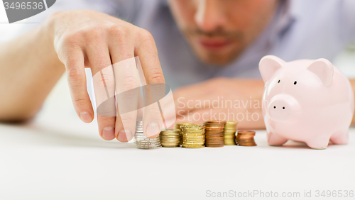 Image of close up of businessman with piggy bank and coins