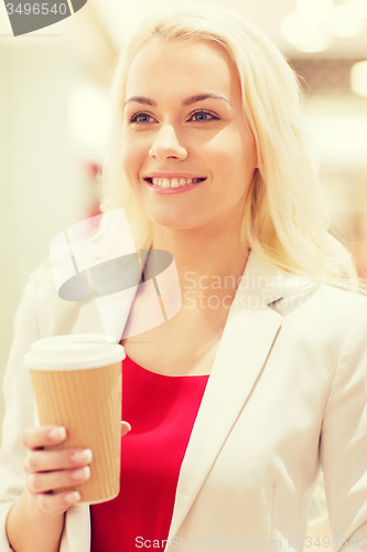 Image of happy young woman with coffee paper cup in mall