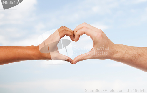 Image of woman and man hands showing heart shape