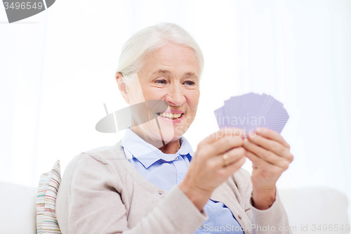 Image of happy senior woman playing cards at home