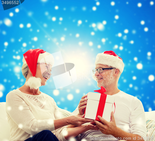 Image of happy senior couple with gift box at home