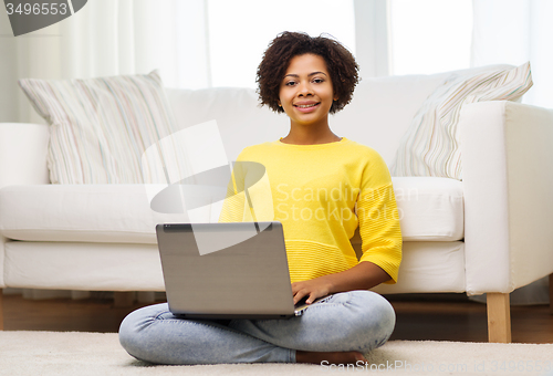 Image of happy african american woman with laptop at home