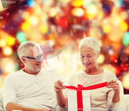 Image of happy senior couple with gift box at home